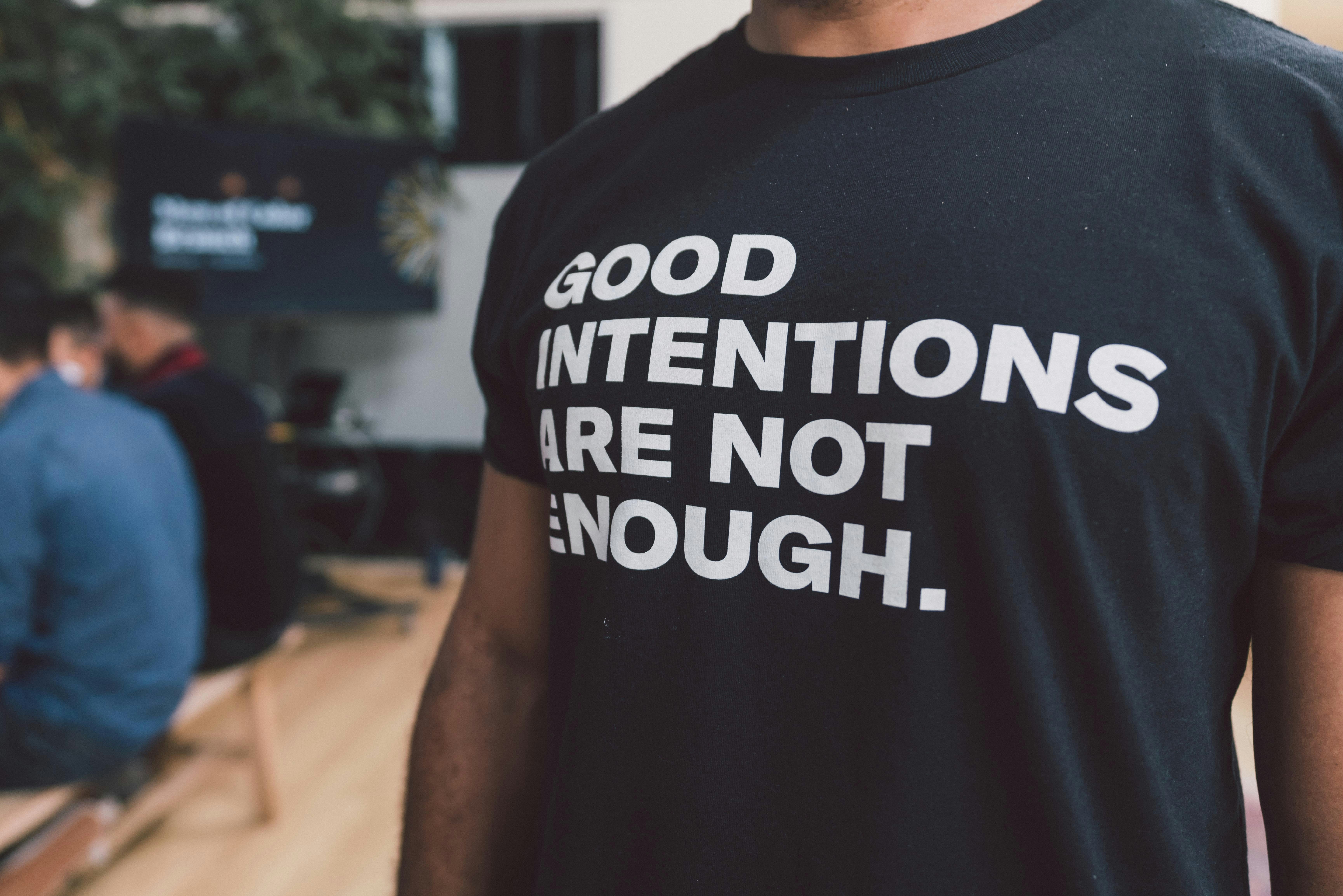 Person wearing a shirt that says, "Good intentions are not enough."