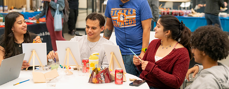 a group of students painting and eating at a table