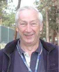 older white men with white hair smiling outside in blue collared shirt with jacket