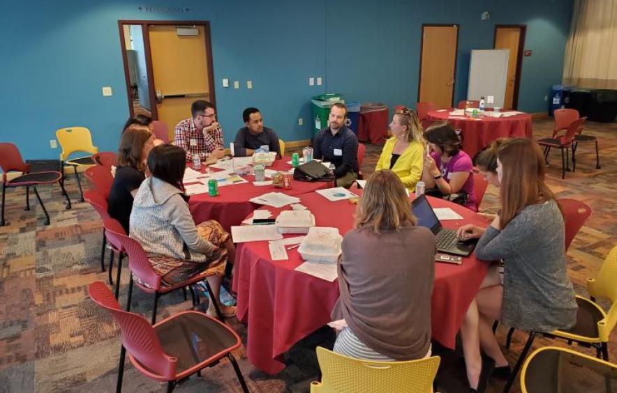 group of people sitting around a round table eating