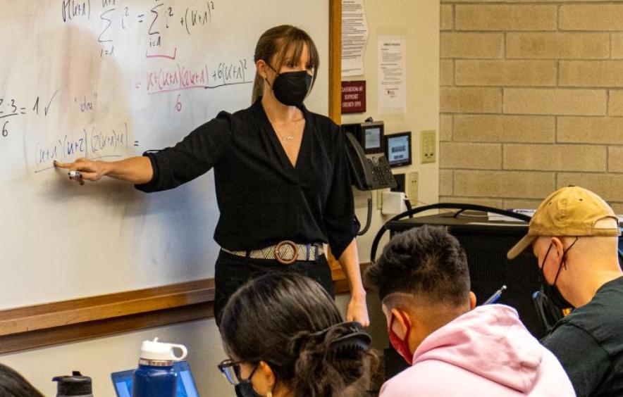 Female-presenting teacher pointing to whiteboard