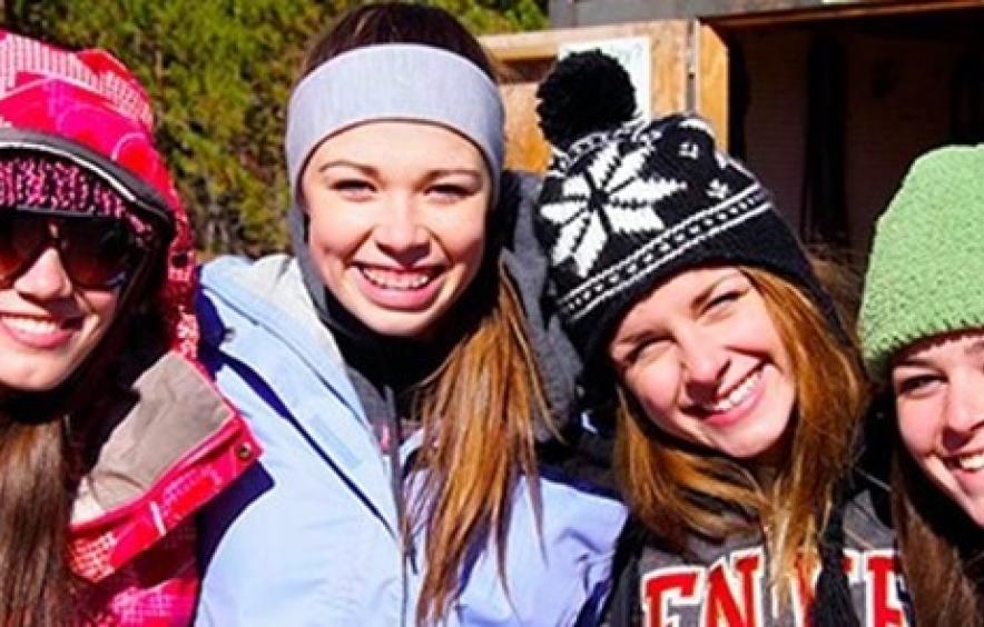 Four female-presenting individuals smiling at the camera