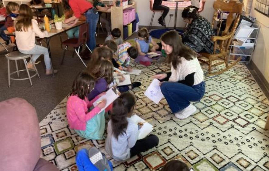 group of young students sitting on a rug on the floor