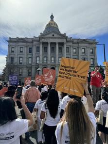 Photo of the Cocina Libre team marching with thousands at the Colorado State Capitol on March 17, 2025, raising signs and uniting voices for immigrant and reproductive justice, highlighting the interconnectedness of these struggles.