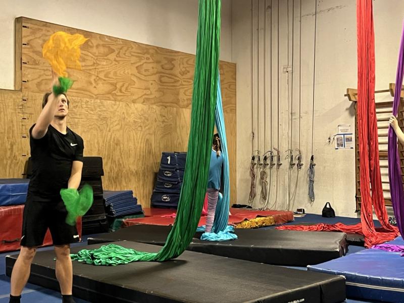 Several gymnasts performing routines in a gym, highlighting their athleticism and collaboration in a vibrant training environment.