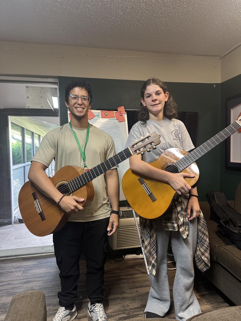 CE Scholar and music student posing for a photo with their acoustic guitars