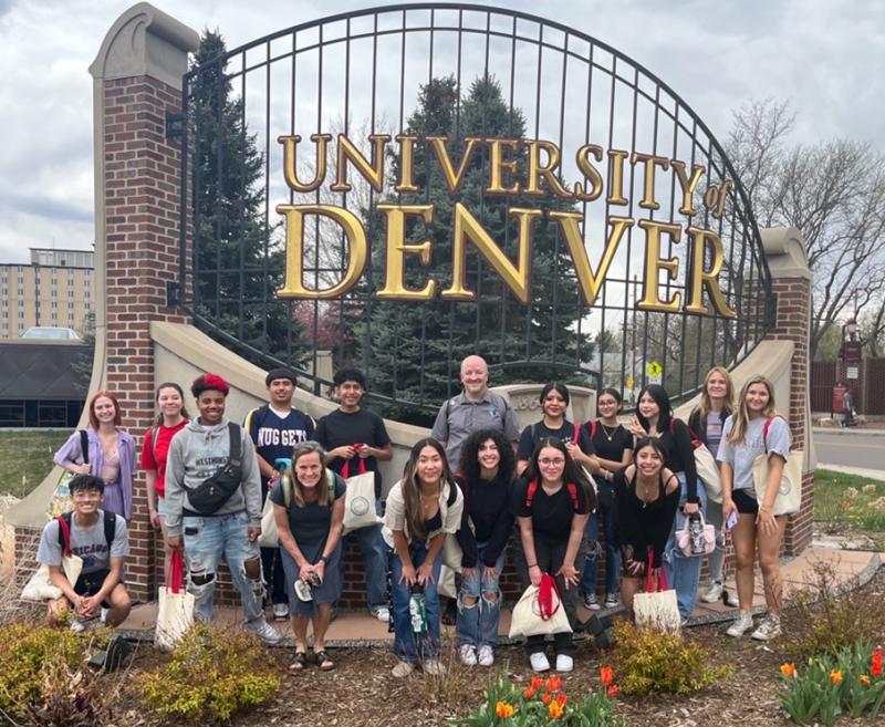 Group standing in front of sign that says University of Denver