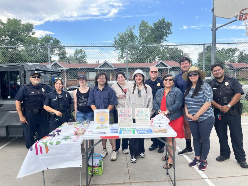 Photo of a group of people posing in front of a table and chain fence
