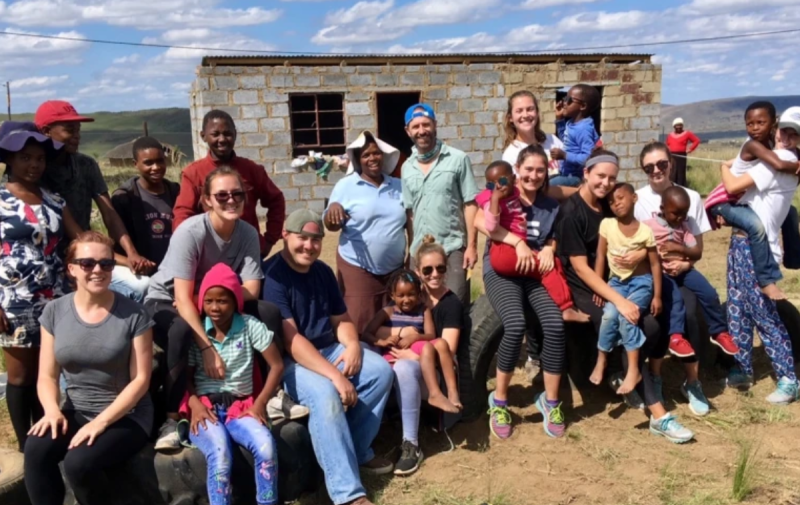 large group of people sitting in front of a brick house