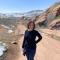 Emily G: A photo of Emily in a black sweater; image taken near Red Rocks Ampitheatre with snow and red rock formations in the background.