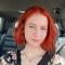 Nicole D: A photo of a woman with red hair smiling in the passenger seat of a car