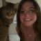a brown haired girl with glasses smiling into camera with a cat