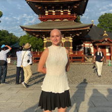 Woman stands in front of a pagoda 