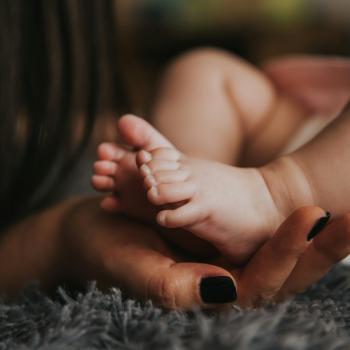 Mother holding baby's feet gently