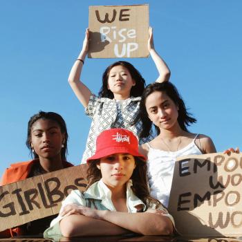 Group of young women holding handmade signs promoting empowerment