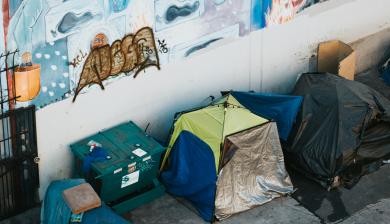 aerial view of three tents backed against a concrete wall with graffiti