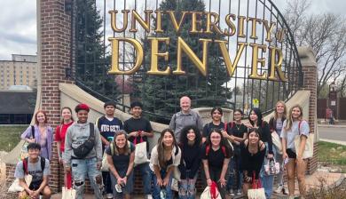 Group standing in front of sign that says University of Denver