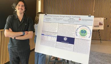 Mateo standing next to his poster presentation at the Public Good Celebration.
