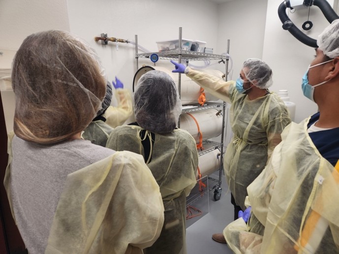 People standing in high altitude physiology lab wearing gowns, gloves, and hair nets